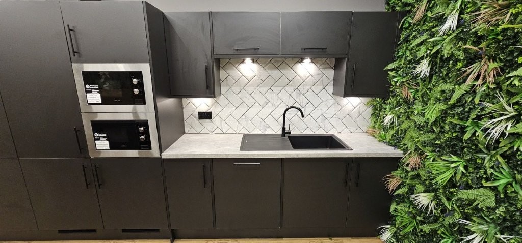 Black sink, undercabinet lighting, integrated microwaves and stunning tiling